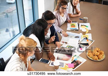 Stock Photography - Colleagues having meeting at conference room table. Fotosearch