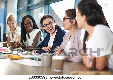Stock Photography - Colleagues having meeting at conference room table. Fotosearch