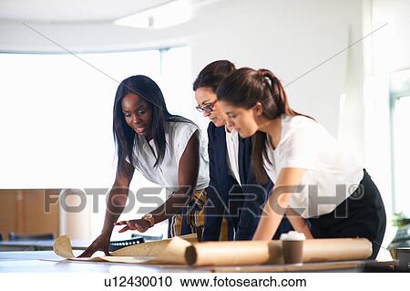 Colleagues in office looking at blueprint View Large Photo Image Stock Image - Colleagues in office looking at blueprint. Fotosearch