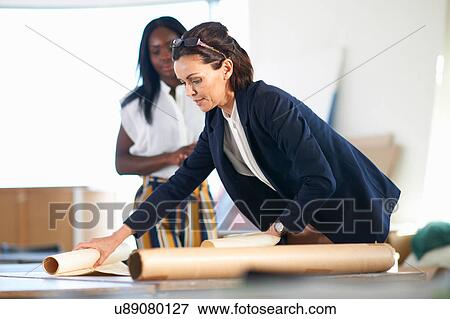 Stock Photo - Colleagues in office looking at blueprint. Fotosearch