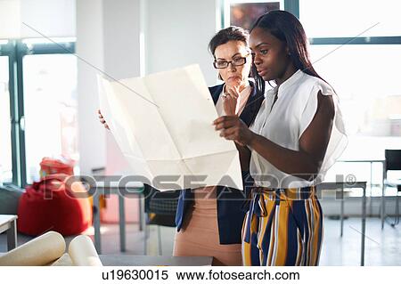 Stock Photography - Colleagues in office looking at blueprint. Fotosearch