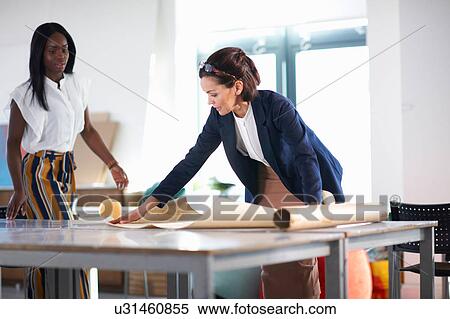 Colleagues in office looking at blueprint View Large Photo Image Stock Photography - Colleagues in office looking at blueprint. Fotosearch