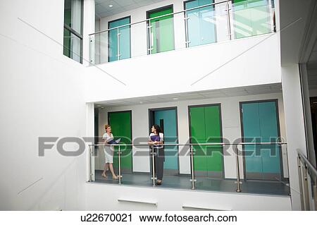 Stock Image - Colleagues on balcony in office building. Fotosearch