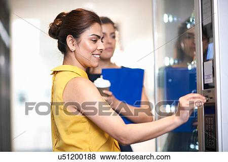 Colleagues using vending machine chatting View Large Photo Image Stock Photo - Colleagues using vending machine chatting. Fotosearch