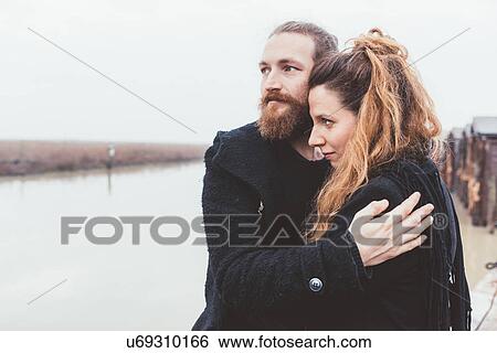 Stock Photograph - Couple hugging on misty canal waterfront. Fotosearch