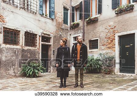 Couple in courtyard looking in opposite directions, Venice, Italy View Large Photo Image Stock Photo - Couple in courtyard looking in opposite directions, Venice, Italy. Fotosearch