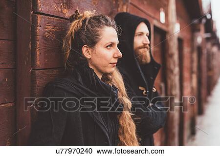Stock Image - Couple leaning against huts, gazing out. Fotosearch