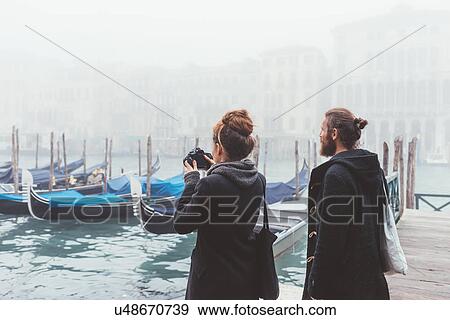 Couple photographing gondolas on misty canal, Venice, Italy View Large Photo Image Stock Photo - Couple photographing gondolas on misty canal, Venice, Italy. Fotosearch