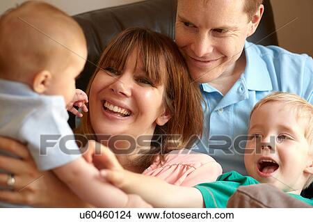 Picture - Couple with boy and baby son on sofa together. Fotosearch