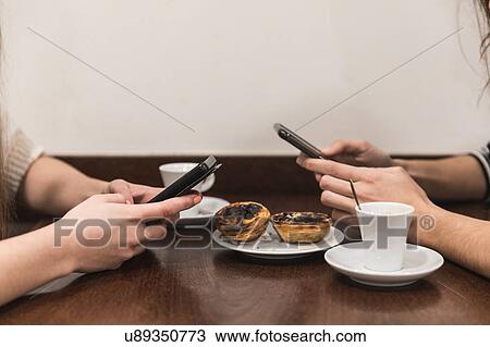 Cropped view of friends at table texting on smartphones View Large Photo Image Stock Image - Cropped view of friends at table texting on smartphones. Fotosearch