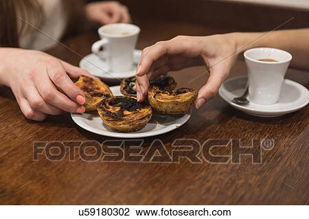 Stock Image - Cropped view of friends picking pastries from plate. Fotosearch