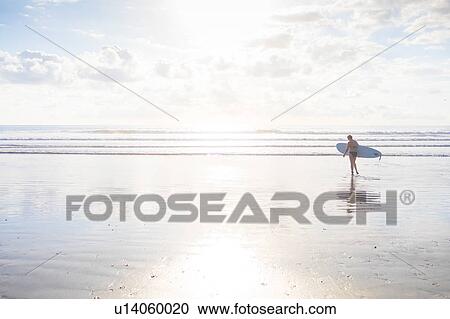 Distant view of woman carrying surfboard on beach, Nosara, Guanacaste Province, Costa Rica View Large Photo Image Stock Image - Distant view of woman carrying surfboard on beach, Nosara, Guanacaste Province, Costa Rica. Fotosearch