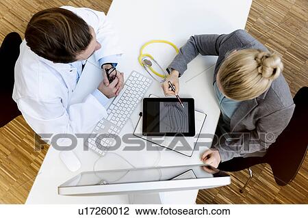 Doctor in meeting with consultant, overhead view View Large Photo Image Stock Image - Doctor in meeting with consultant, overhead view. Fotosearch
