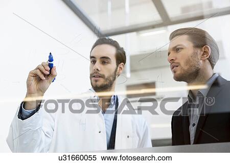 Stock Photography - Doctor meeting with consultant, writing on glass whiteboard. Fotosearch