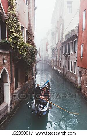Stock Photo - Elevated view of gondolier on misty canal, Venice, Italy. Fotosearch