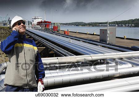 Engineer on cell phone with pipelines View Large Photo Image Stock Image - Engineer on cell phone with pipelines. Fotosearch