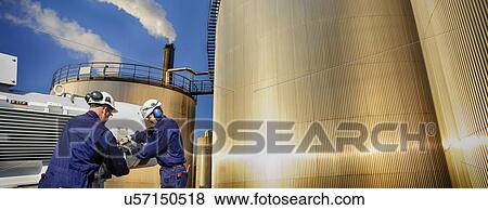 Stock Photo - Engineers by oil storage towers. Fotosearch