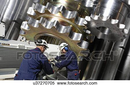 Stock Photography - Engineers working with metal cogs. Fotosearch