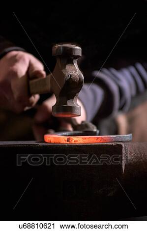 Stock Image - Farrier forging horseshoe on anvil. Fotosearch