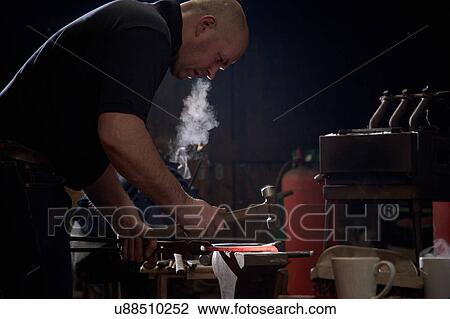 Stock Image - Farrier forging horseshoe on anvil. Fotosearch