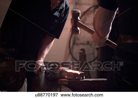 Stock Photo - Farriers forging horseshoe on anvil. Fotosearch
