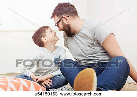 Father and son sitting on floor smiling at each other View Large Photo Image Stock Image - Father and son sitting on floor smiling at each other. Fotosearch