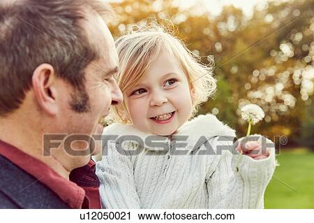 Father carrying daughter holding dandelion clock View Large Photo Image Stock Image - Father carrying daughter holding dandelion clock. Fotosearch