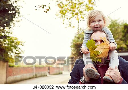 Stock Image - Father carrying daughter on shoulders. Fotosearch