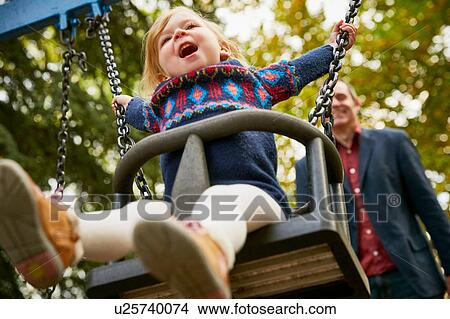 Father pushing daughter on playground swing View Large Photo Image Picture - Father pushing daughter on playground swing. Fotosearch