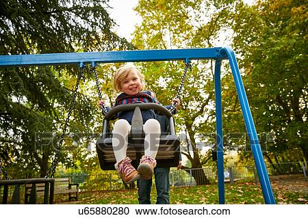 Father pushing daughter on playground swing View Large Photo Image Stock Image - Father pushing daughter on playground swing. Fotosearch