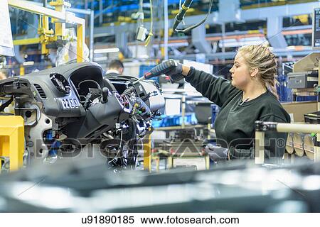 Stock Photography - Female apprentice engineer on production line in car factory. Fotosearch