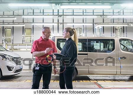 Picture - Female apprentice engineer with mentor on production line in car factory. Fotosearch