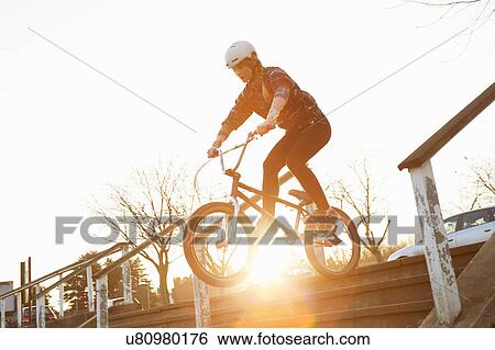 Stock Photograph - Female BMX rider riding down sunlit stairway. Fotosearch
