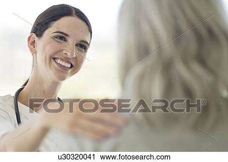 Stock Image - Female care worker smiling towards patient. Fotosearch