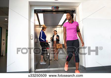 Female colleagues taking office lift View Large Photo Image Stock Photo - Female colleagues taking office lift. Fotosearch