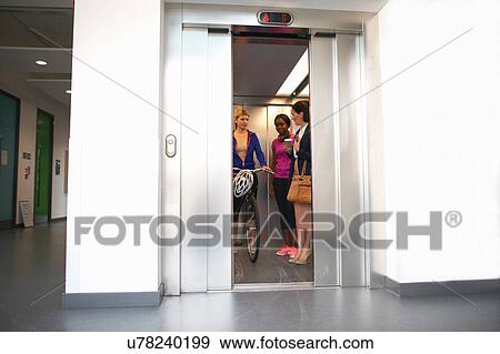 Female colleagues taking office lift View Large Photo Image Stock Photo - Female colleagues taking office lift. Fotosearch