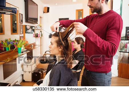 Stock Photography - Female customer having long brown hair trimmed in hair salon. Fotosearch