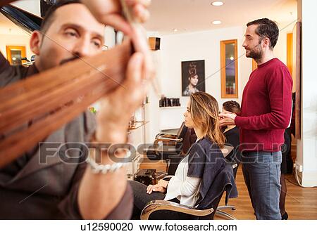Stock Image - Female customer having long red hair trimmed in hair salon. Fotosearch