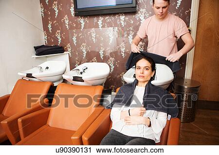 Stock Image - Female customer with wet hair at salon sink. Fotosearch