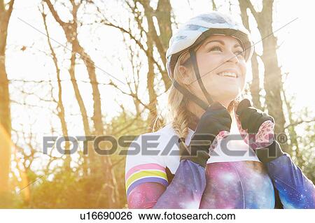 Female cyclist fastening helmet in park View Large Photo Image Stock Photograph - Female cyclist fastening helmet in park. Fotosearch