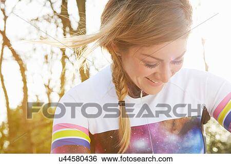 Stock Photograph - Female cyclist looking down in park. Fotosearch