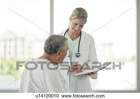 Stock Image - Female doctor and senior man in hospital. Fotosearch