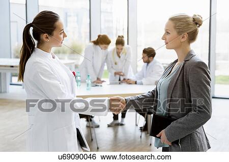 Female doctor shaking hands with consultant View Large Photo Image Stock Photograph - Female doctor shaking hands with consultant. Fotosearch