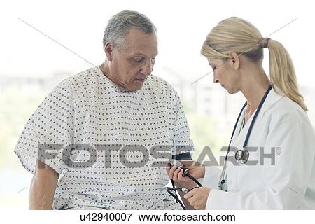 Female doctor taking senior man's blood pressure View Large Photo Image Stock Photo - Female doctor taking senior man's blood pressure. Fotosearch
