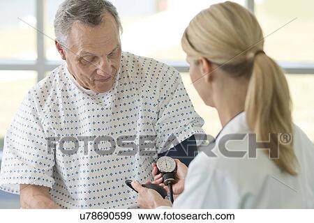 Female doctor taking senior man's blood pressure View Large Photo Image Stock Photo - Female doctor taking senior man's blood pressure. Fotosearch