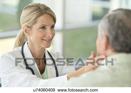 Stock Photo - Female doctor touching senior man's neck. Fotosearch