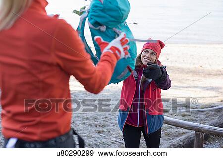 Stock Photo - Female hiker throwing backpack to friend on lakeside in Bavarian Alps. Fotosearch