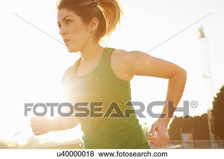 Stock Photo - Female runner running in sunlit park. Fotosearch