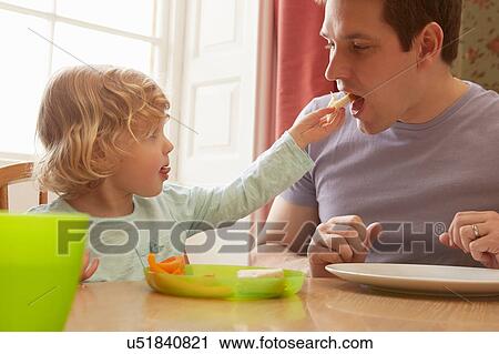 Female toddler feeding bread to father at kitchen table View Large Photo Image Stock Image - Female toddler feeding bread to father at kitchen table. Fotosearch