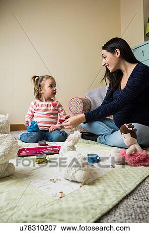 Female toddler sitting on floor with pregnant mother playing picnics with soft toys View Large Photo Image Stock Photo - Female toddler sitting on floor with pregnant mother playing picnics with soft toys. Fotosearch